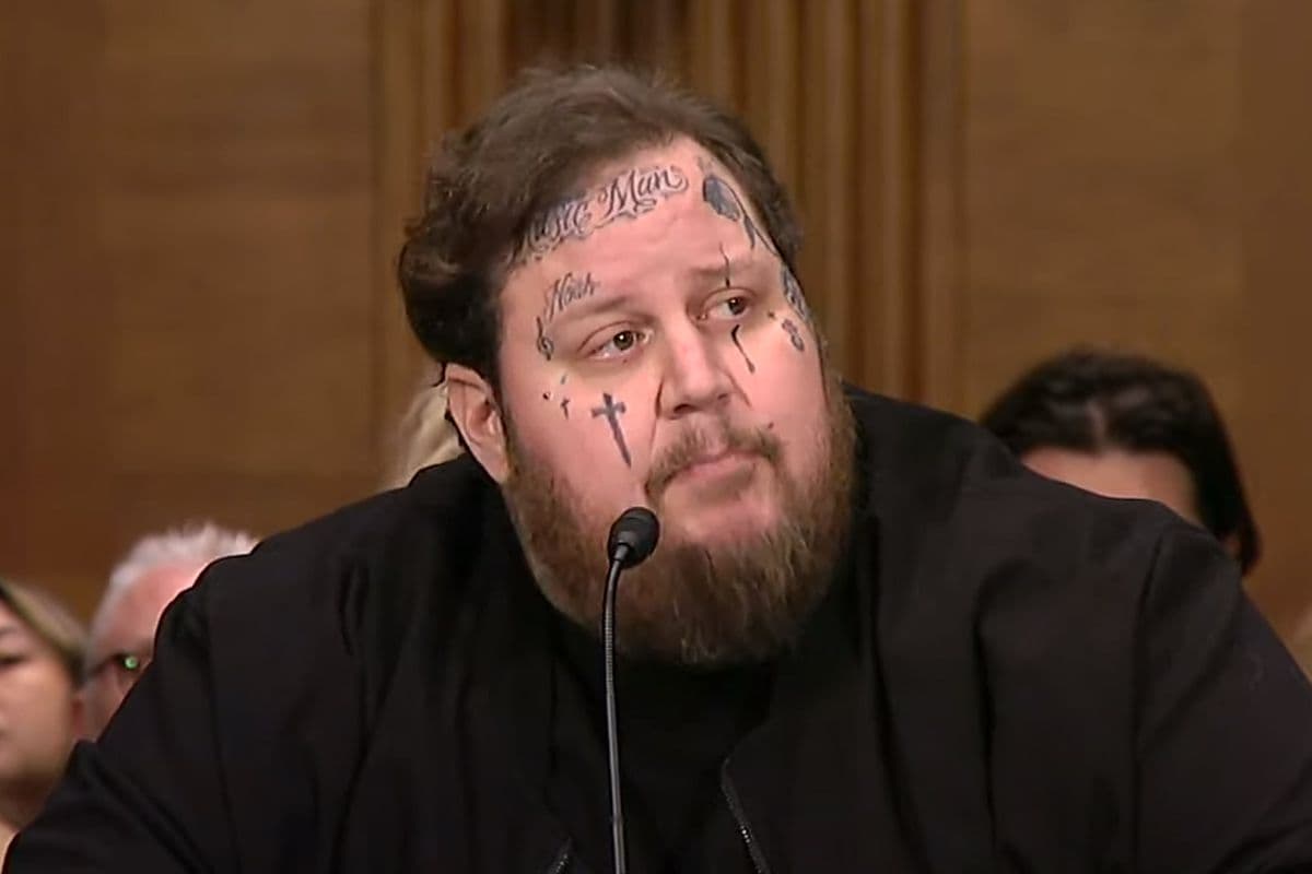 A man in tattoos sits in front of a microphone